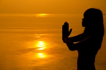 Woman with namaste hands at sunset